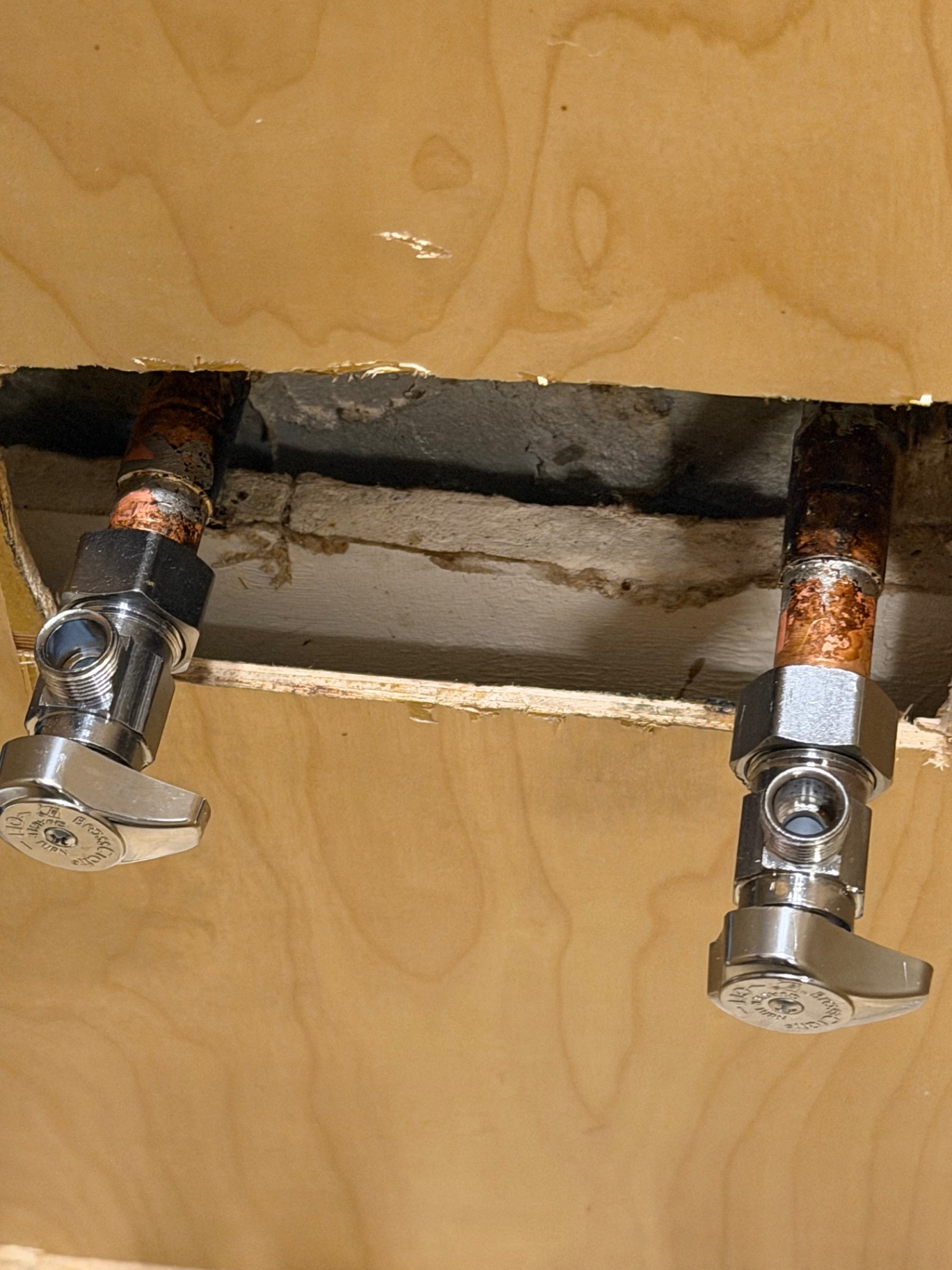 New chrome quarter-turn angle stop valves soldered onto copper stub-outs behind a vanity by Better Call Sam Plumbing