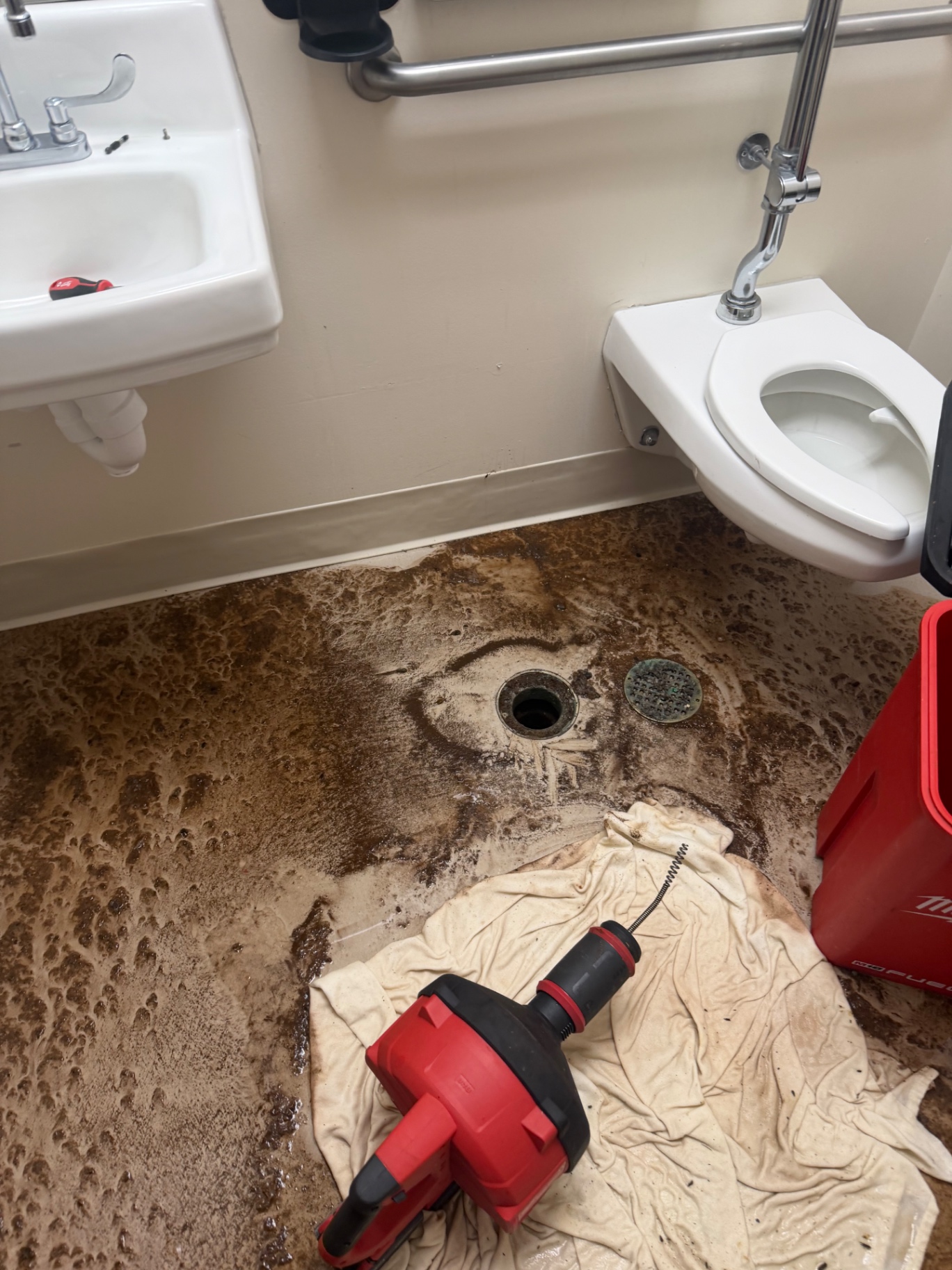 Commercial restroom floor drain being cleared with a Milwaukee M18 drain machine by Better Call Sam Plumbing